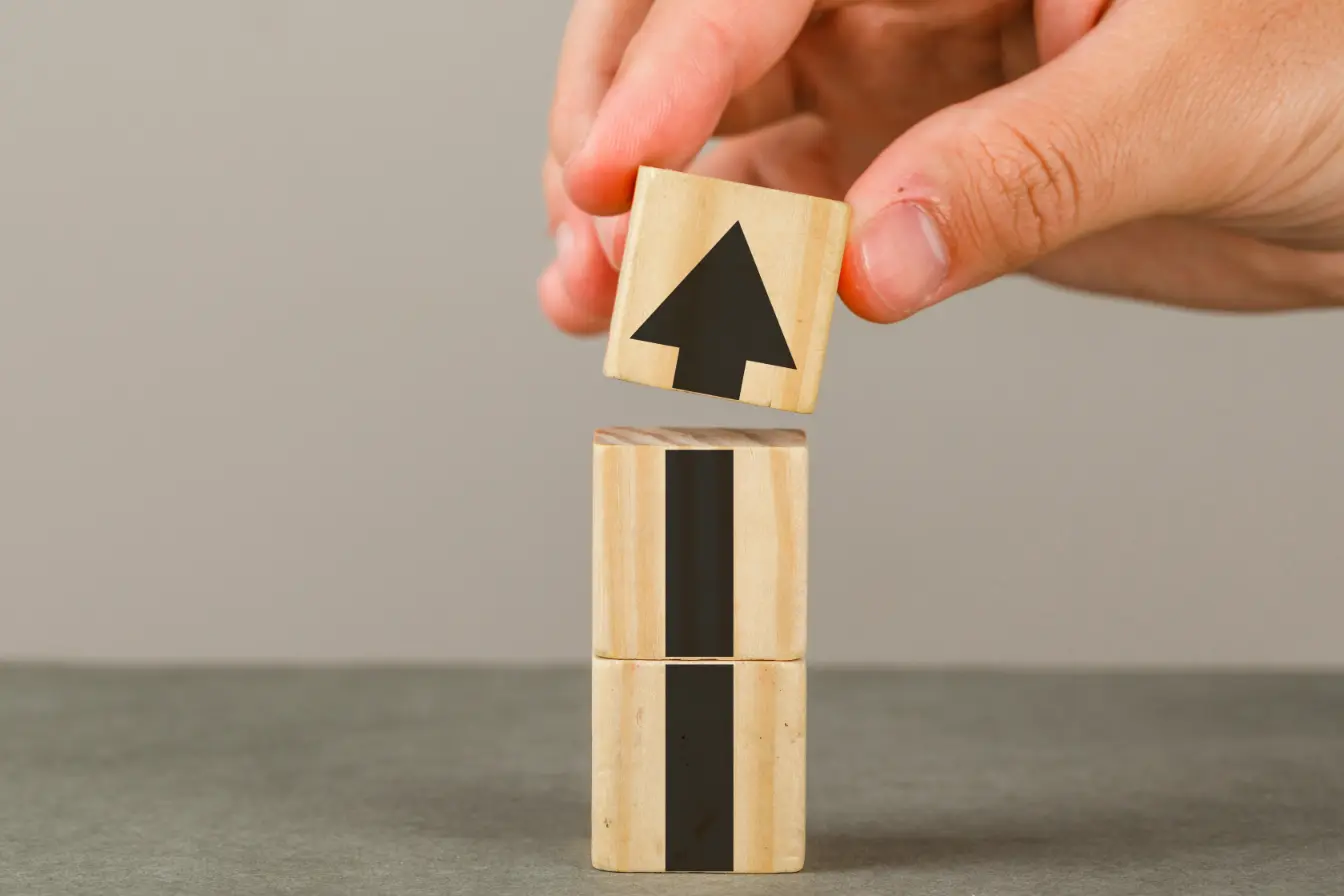 business-growth-concept-grey-white-wall-side-view-hand-putting-wood-block-onto-tower